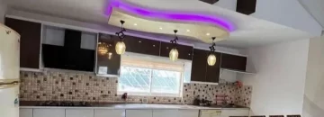 کابینت های سفید قهوه ای و سقف نور پردازی شده با نور بنفش آشپزخانه ویلا در چالوس